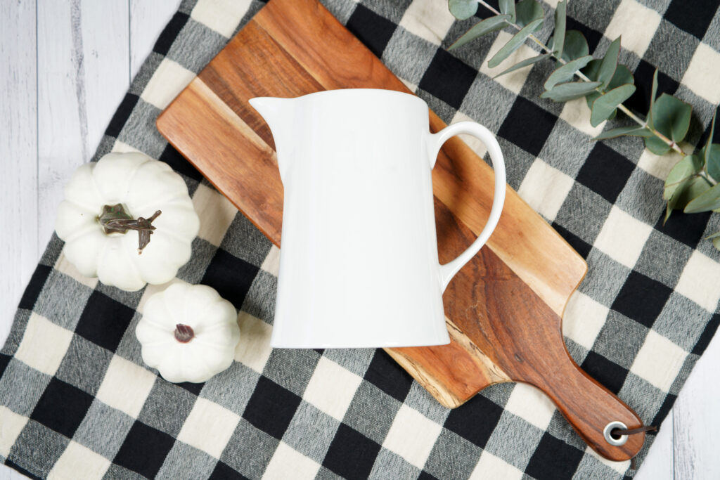 Ceramic Pitcher on a cuttingboard with pumpkins and plaid towel
